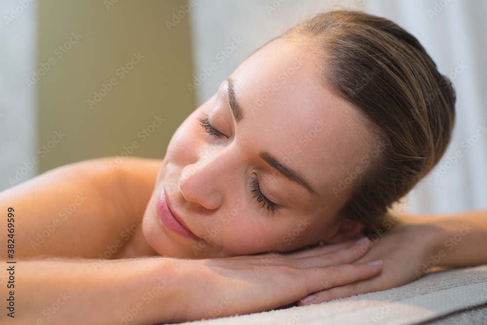 smiling woman in a day spa relaxing on massage table smiling woman in a day spa relaxing on massage table