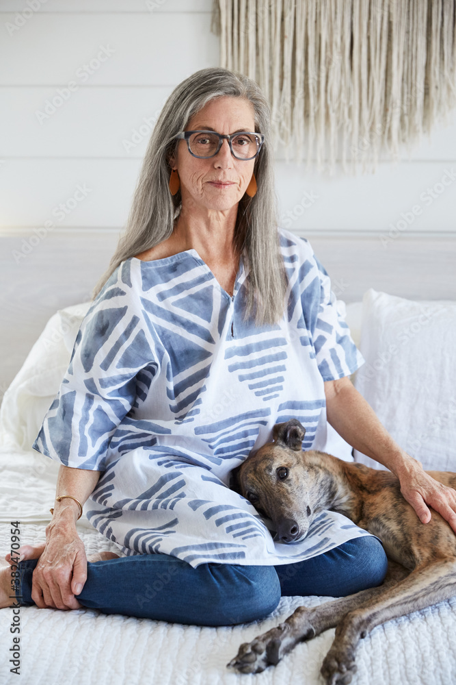 Senior woman with grey hair with her dog at home