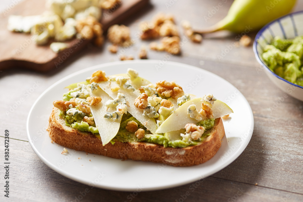Close-up of fresh tasty avocado toast with blue cheese,nuts and pear Close-up of fresh tasty avocado toast with blue cheese,nuts and pear