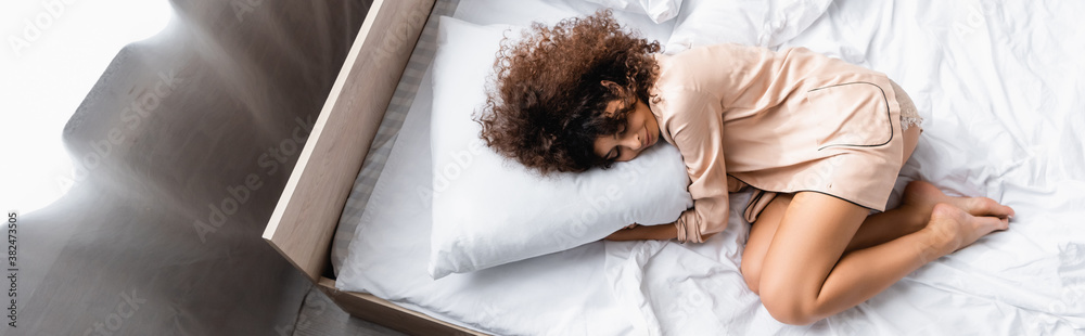 panoramic concept of barefoot woman with closed eyes hugging pillow while sleeping on bed panoramic concept of barefoot woman with closed eyes hugging pillow while sleeping on bed