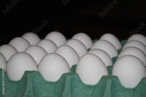 Ovos brancos com casca em uma cartela verde photo