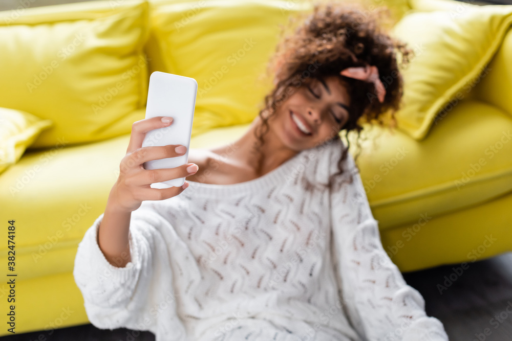 selective focus of joyful woman taking selfie in living room