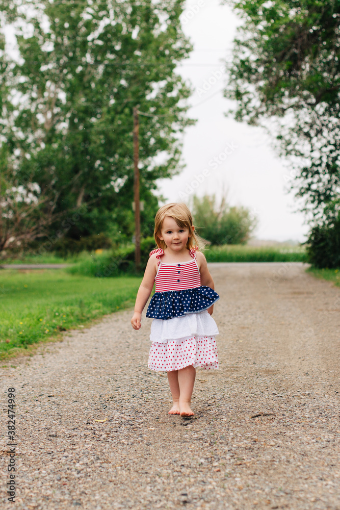 Toddler girl walking barefooted down a gravel driveway. Toddler girl walking barefooted down a gravel driveway.