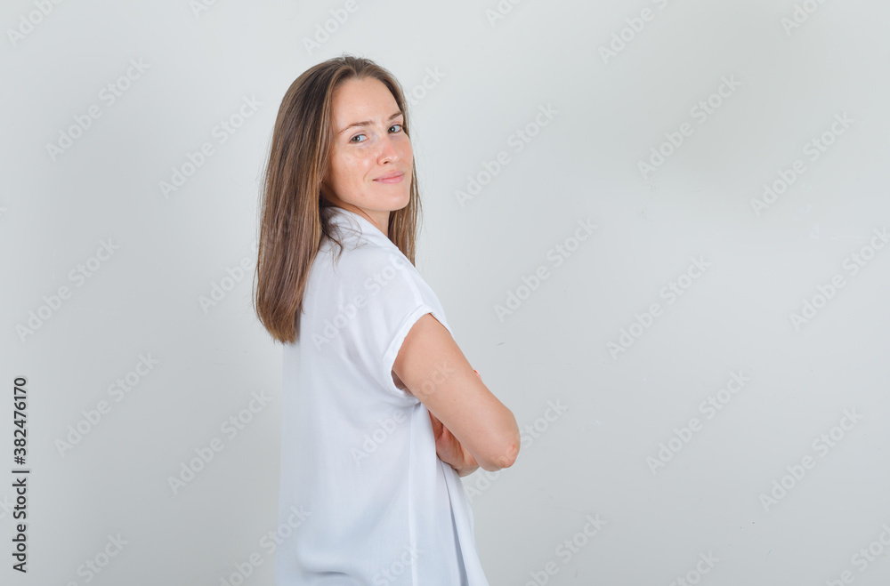 Young woman standing with crossed arms in white t-shirt and looking confident . Young woman standing with crossed arms in white t-shirt and looking confident .