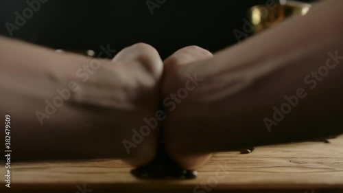 Human hands spread handfuls of dark roasted coffee beans from jute bag, lying on wood desk. Genuine coffee mill and cezve on the background. Slow motion, zoom out
