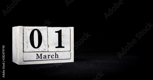 March 1st, First of March, Day 1 of month March - white calendar blocks on black textured background with empty space for text.