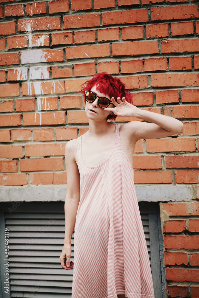 Portrait of a young fashionable female with bright red hair in sunglasses Portrait of a young fashionable female with bright red hair in sunglasses