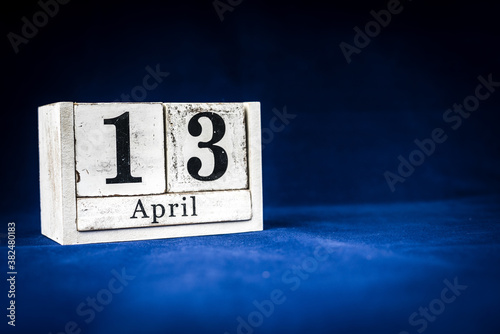 April 13th, Thirteenth of April, Day 13 of month April - rustic wooden white calendar blocks on dark blue background with empty space for text.