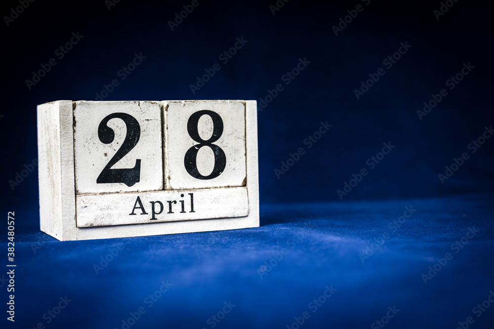April 28th, Twenty-eighth of April, Day 28 of month April - rustic wooden white calendar blocks on dark blue background with empty space for text. April 28th, Twenty-eighth of April, Day 28 of month April - rustic wooden white calendar blocks on dark blue background with empty space for text.