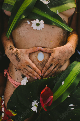 Beautiful naked female body covered with tropical flowers and plant