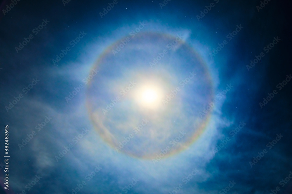 Super moon with a circular rainbow halo formed by the mist Bblue foggy night with diffused moonlight and stars
