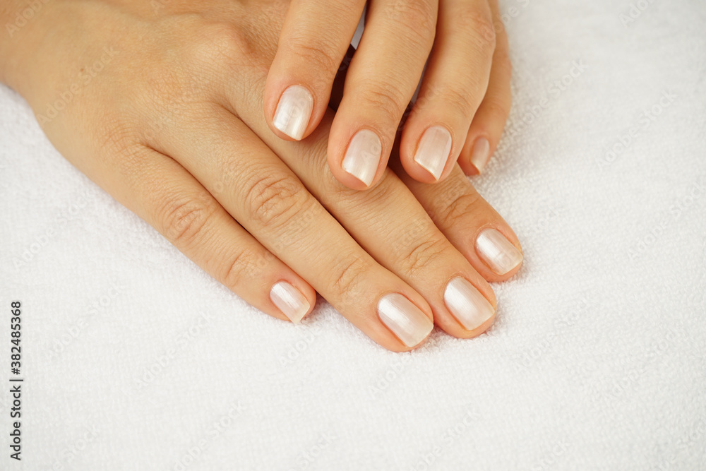 beautiful female hands with well-groomed manicure lie on a white terry towel