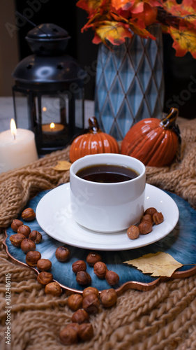 Autumn background with coffee, knitted scarf, pumpkin. Autumn coffee, dry leaves. Season October, November.