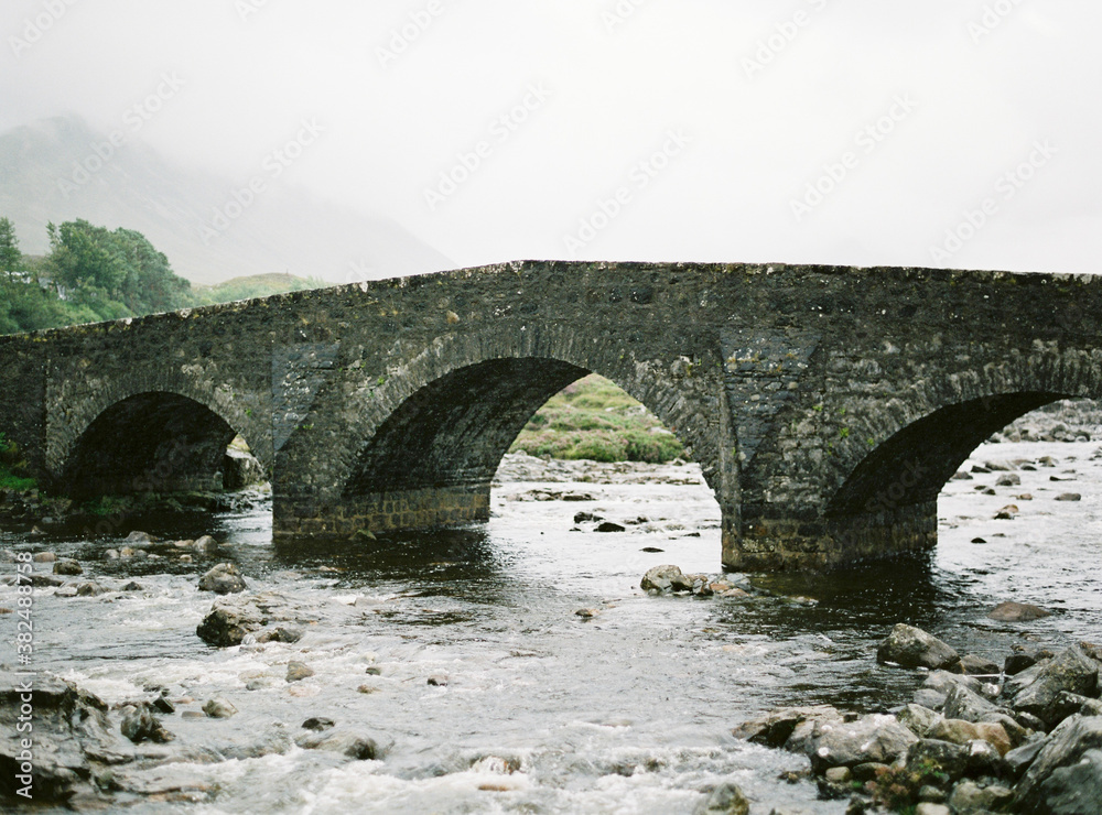 Old stone bridge over river in foggy countryside Old stone bridge over river in foggy countryside