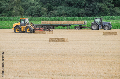 Wheel loader collecting straw bales and loading them onto a trac photo