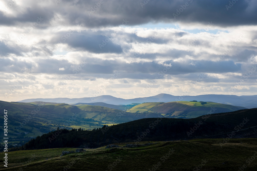 Obraz premium a mountainous view of the mountains in Powys looking into Gwyneth with the rolling hills and mountains lit up by the sunlight