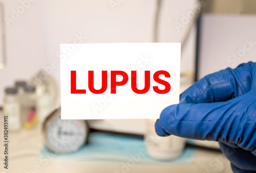 Doctor's hands in blue gloves shows the word lupus. Medical concept.