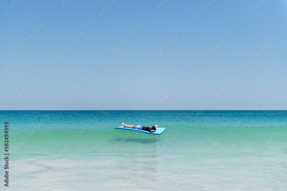 Relaxing on a mat on water at the beach in summer Relaxing on a mat on water at the beach in summer