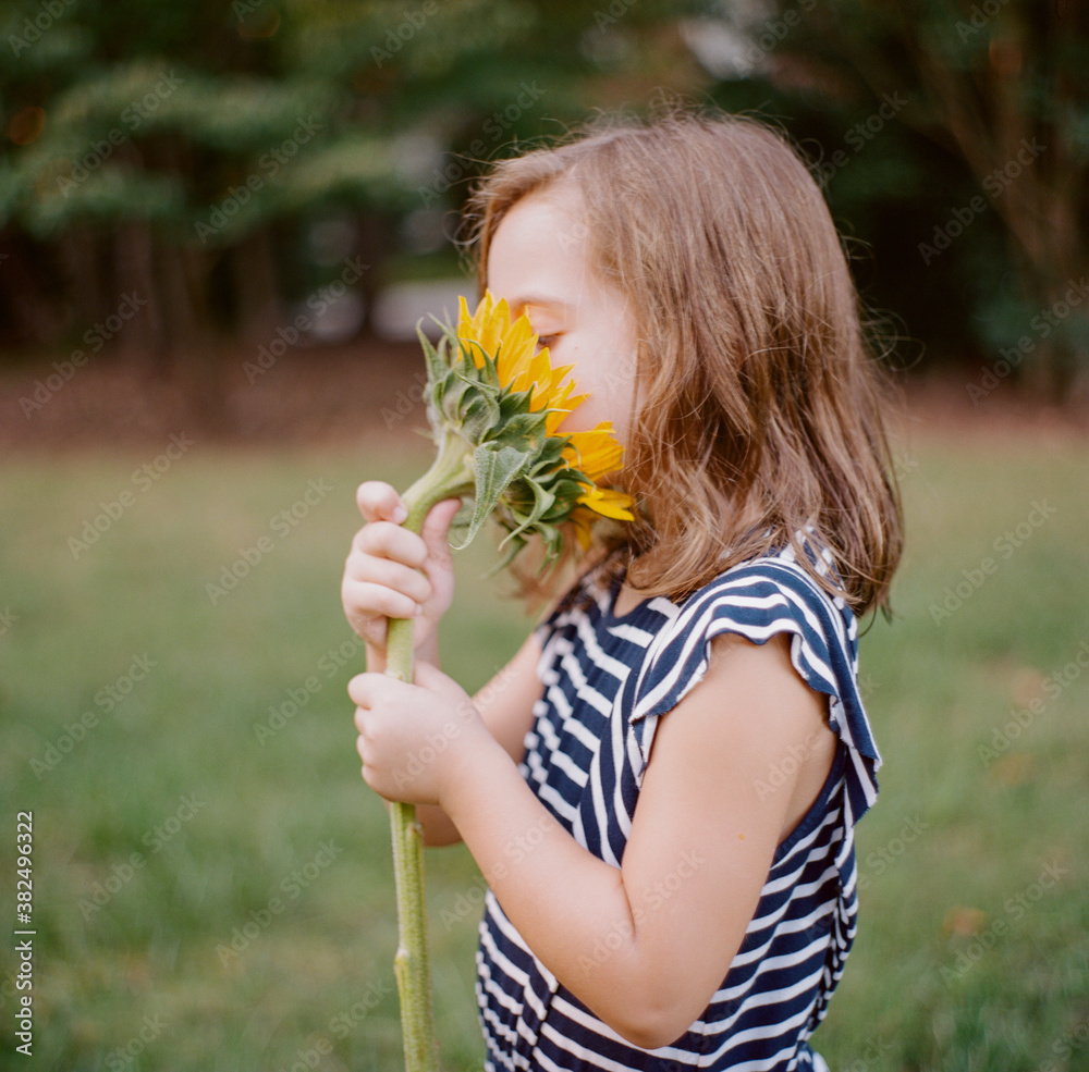 Cute young girl with her face in big sunflower