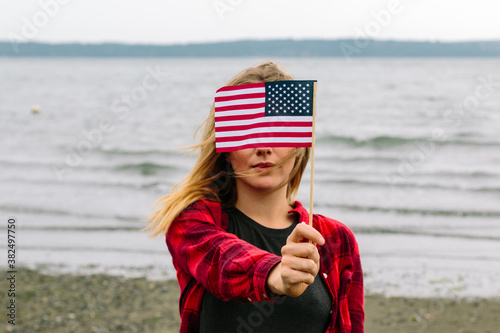 Young Woman On Ocean Beach Holding Mini American Flag In Front O photo