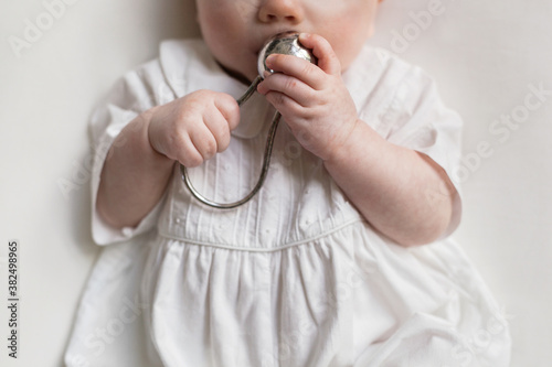 baby holding a silver rattle