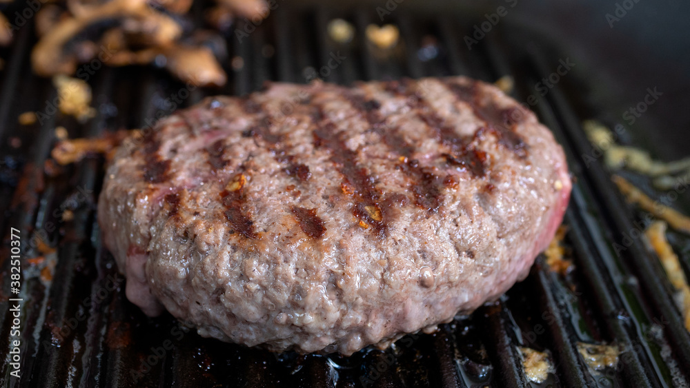 Hamburger patty getting cooked in a cast iron grill pan. Charred burn marks  from the pan are clearly visible. Hamburger meat and food preparation  concept. Stock-Foto | Adobe Stock