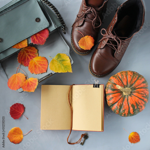 Autumn still life with a bag, leaves, shoes, orange pumpkin and notebook with copy space. Art creative background for mockup