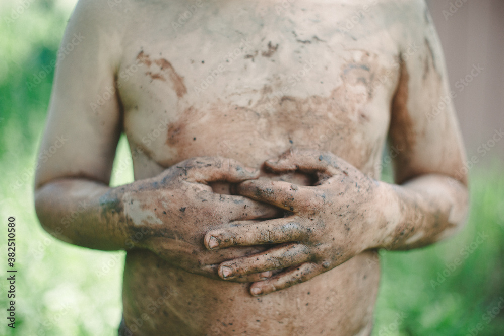 Body of a boy covered in mud
