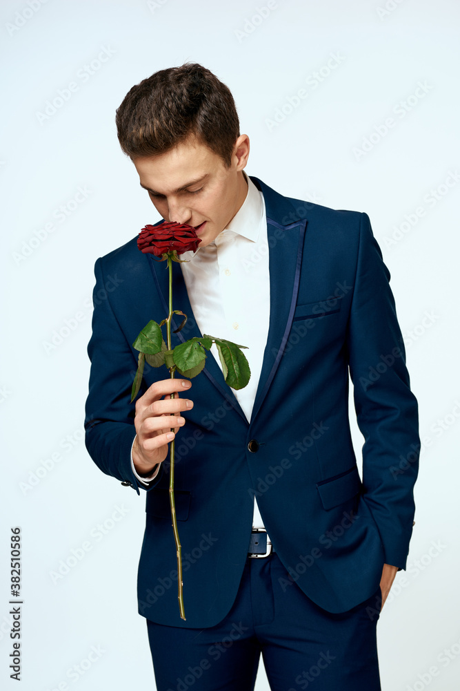 A man in a suit with a rose in his hands a gift date light background