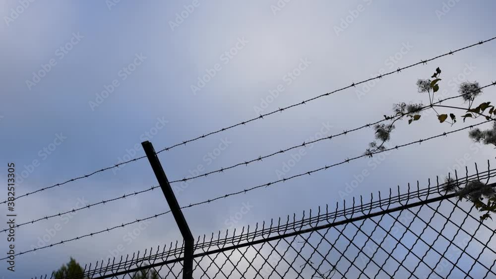 Low-angle of metal fence built of barbed wire, security Low-angle of metal fence built of barbed wire, security