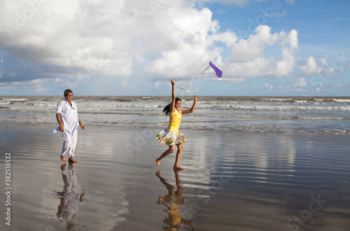 Grandfather and Grandchild enjoying flying kite in sea berach photo