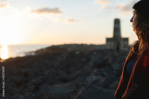 Woman at sunset by the old lighthouse