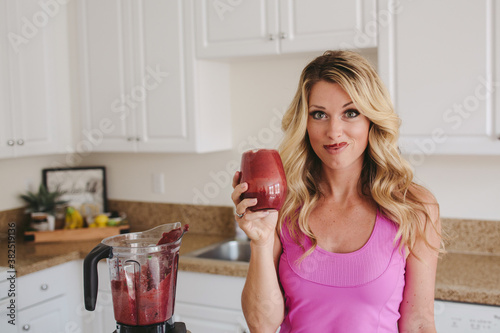 Young woman enjoying smoothie in kitchen - funny moustache