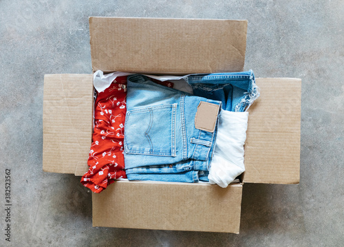 Vintage clothing packed in cardboard box on floor for subscription service mailing photo