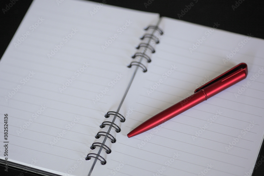 notebook and red pen, with black background notebook and red pen, with black background