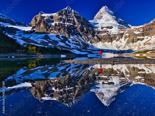 Hiker person walking along the Lake Magog with Mount Assiniboine in the background, British Columbia, Canada photo
