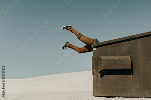 Garbage in, Garbage Out Idiom Concept of human legs flying in the air with his head stuck in the trash