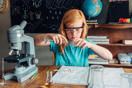 Red haired girl pouring vinegar over baking soda for an experime photo