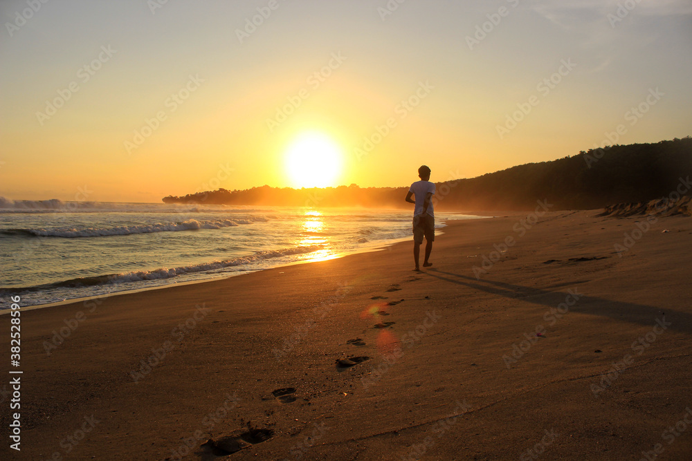 A man walks toward the setting sun, leaving footprints in the sand. Far look from behind.
A man walks toward the setting sun, leaving footprints in the sand. Far look from behind.