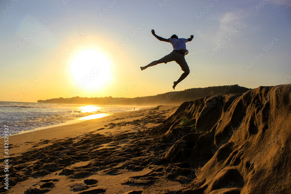 Silhouette of a boy jumping celebrating the sunset.
