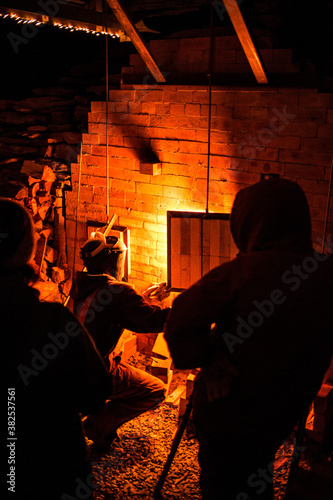 Kiln Worker Stokes Fire During Pottery Making Process