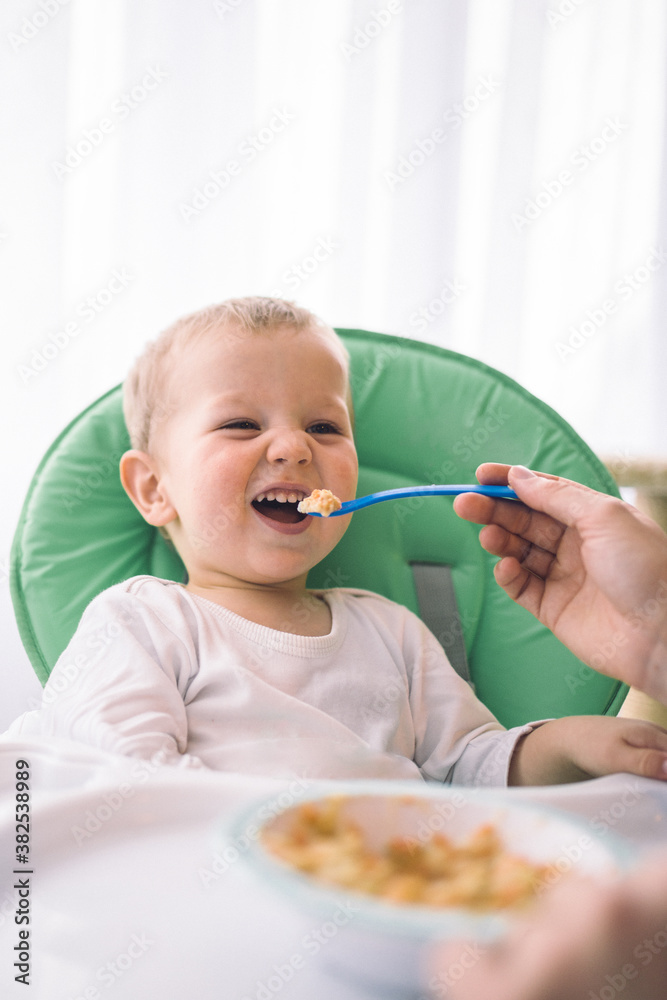 Toddler making faces while eating in his dinner chair Toddler making faces while eating in his dinner chair
