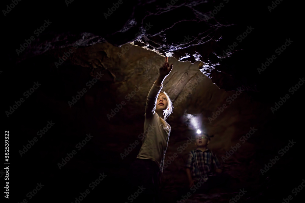 Girl and Boy Exploring A Dark Limestone Cave Underground Girl and Boy Exploring A Dark Limestone Cave Underground