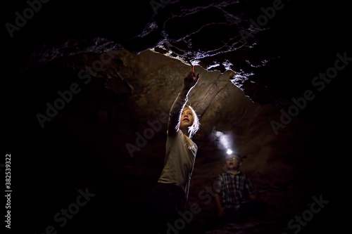 Girl and Boy Exploring A Dark Limestone Cave Underground