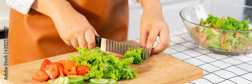 young Asian woman is preparing healthy food vegetable salad by Cutting ingredients on cutting board on light kitchen, Cooking At Home and healthy food concept