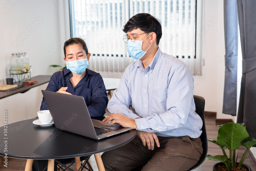 Asian businessman and woman working On Laptop Wearing Face Mask reopening after quarantine for outbreak prevention Coronavirus (Covid-19) New normal culture concept Asian businessman and woman working On Laptop Wearing Face Mask reopening after quarantine for outbreak prevention Coronavirus (Covid-19) New normal culture concept