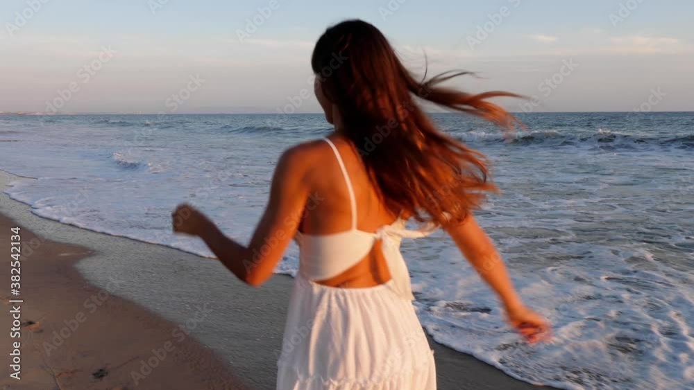 Beautiful woman in a white dress at the beach at sunset Beautiful woman in a white dress at the beach at sunset