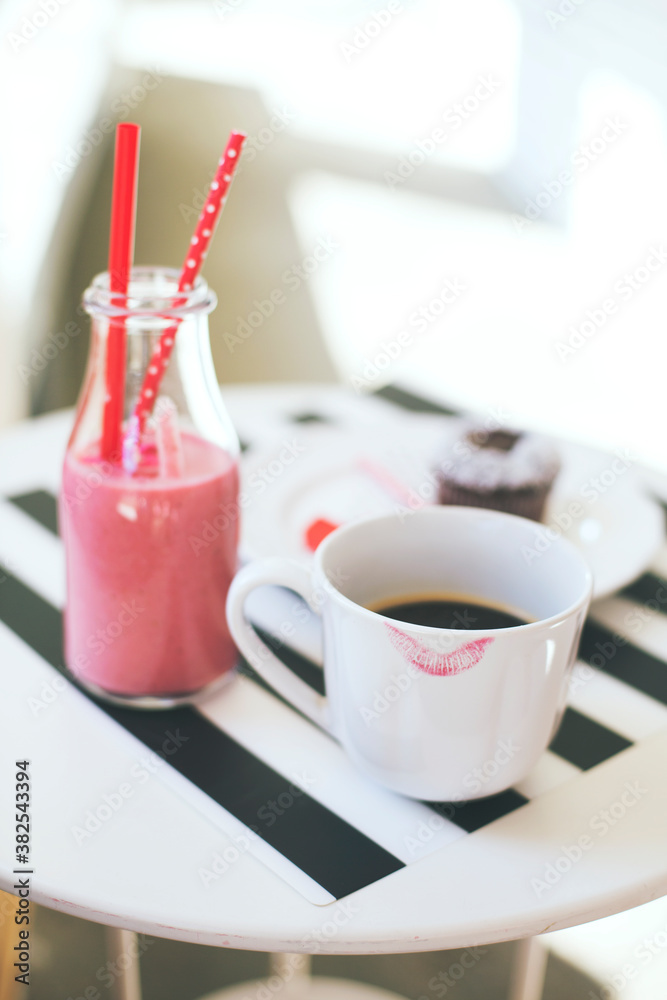 Coffee cup with lipstick print and strawberry smoothie drink on a white table Coffee cup with lipstick print and strawberry smoothie drink on a white table