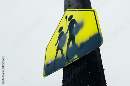 Pedestrian crosswalk sign attached to telephone pole along urban street