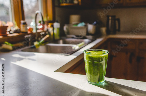 Green smoothie sitting on kitchen counter in the sunlight
